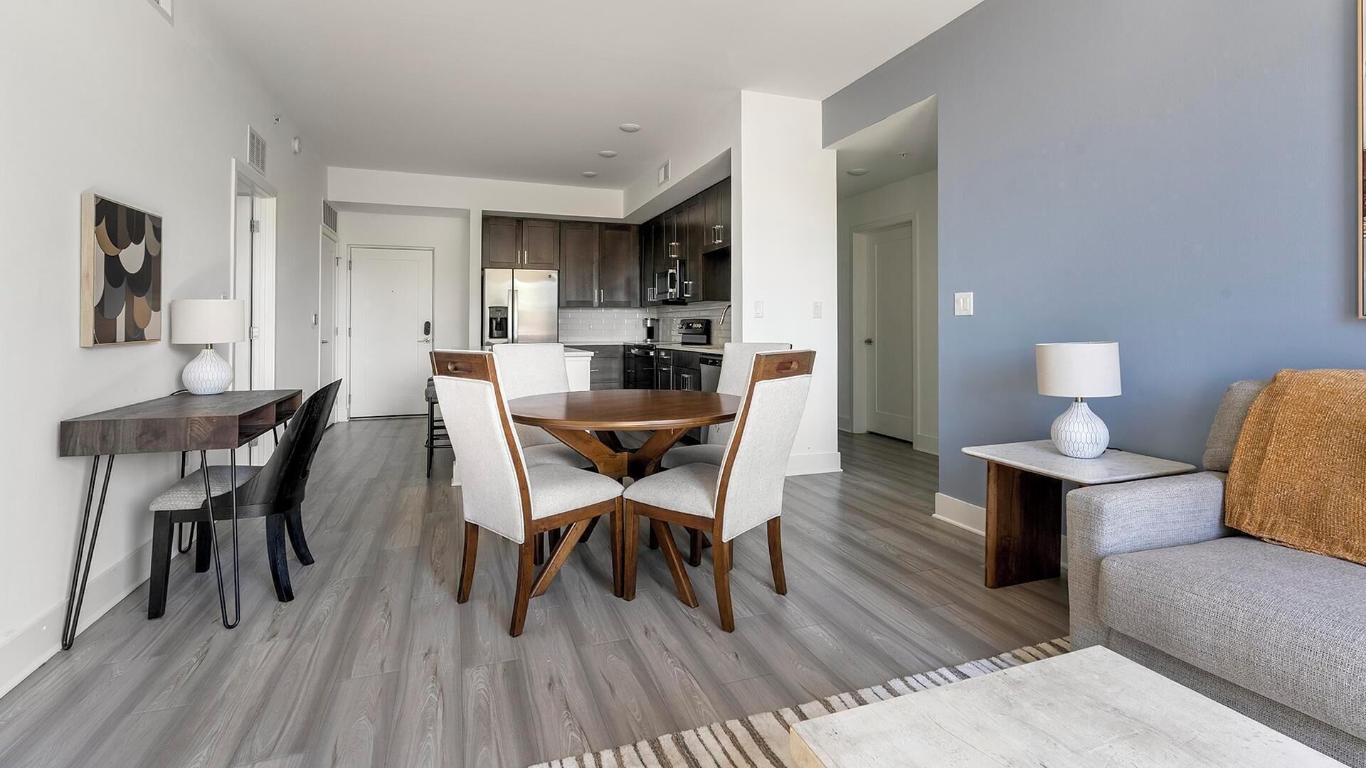 A modern living room with a dining area, a kitchen, and a hallway.