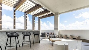 Eine Dachterrasse mit Barbereich, Sitzgelegenheiten und Blick zum Himmel.