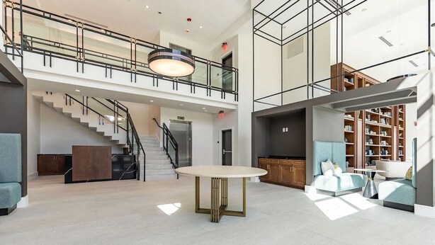 Eine geräumige Lobby mit einer Treppe, einem runden Tisch und Sitzbereichen.