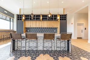 Eine moderne Küche mit Holzschränken, einer schwarz-weißen Küchenrückwand und einer Bar mit Metallhocker.
