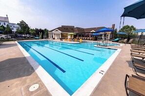 A rectangular swimming pool with lane dividers, surrounded by lounge chairs and umbrellas. - Landing | Chic 2BD, Pool, Gym (Frederick)