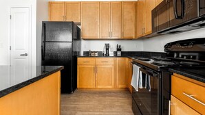 Una cucina con mobili in legno, un frigorifero nero, un fornello e una macchina per il caffè.