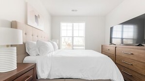 Una camera da letto con un letto, un comodino, una cassettiera, una TV e una finestra con persiane.