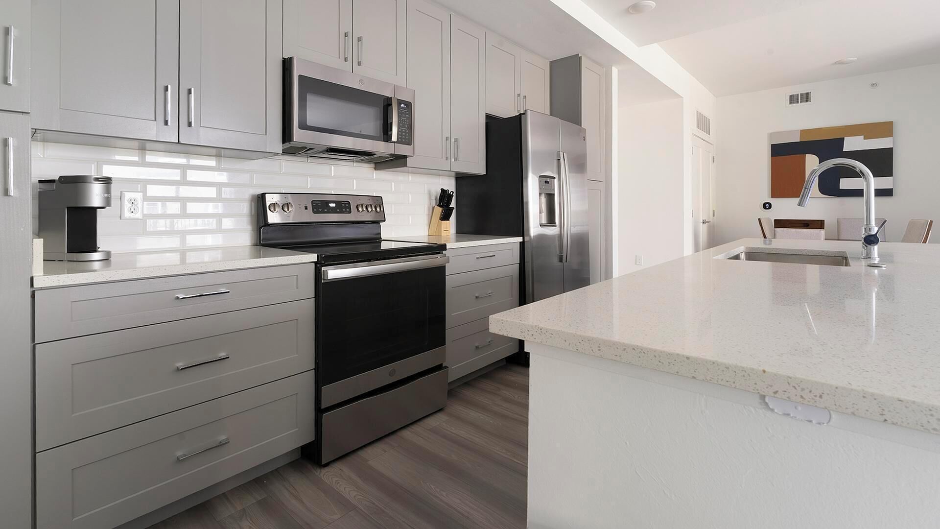 A modern kitchen with stainless steel appliances, white cabinetry, and a granite countertop.