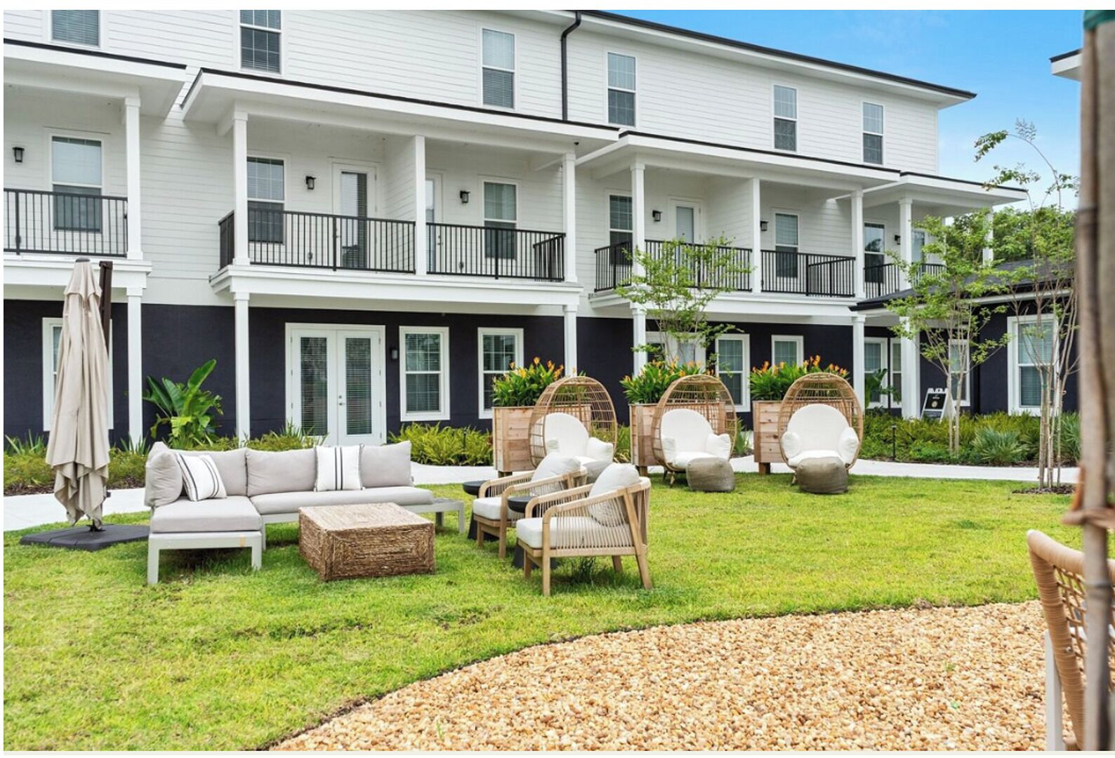 A two-story building with a covered patio area featuring outdoor seating and a small garden.