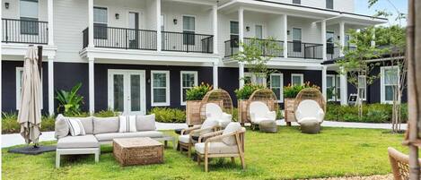 A two-story building with a covered patio area featuring outdoor seating and a small garden.