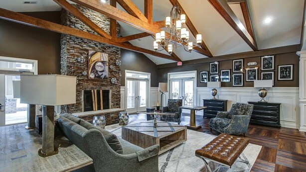 A spacious living room with a stone fireplace, wooden beams, and a chandelier. There are multiple seating areas with sofas and a coffee table. - Landing | Incredible 1BD, Pool, Gym (Greer)