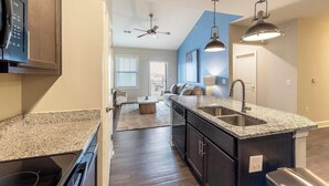 A modern kitchen with granite countertops, stainless steel appliances, and a central island. - Landing | Modern 2BD, Clubhouse, Gym (Greer)