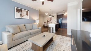 Ein modernes Wohnzimmer mit einer Couch, einem Couchtisch und einer Küche im Hintergrund.