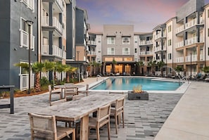 Ein moderner Apartmentkomplex mit einem zentral gelegenen Schwimmbad, Sitzgelegenheiten im Freien und einer Feuerstelle.