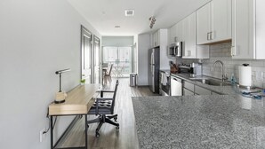 Una cocina moderna con armarios blancos, electrodomésticos de acero inoxidable y encimera de granito.