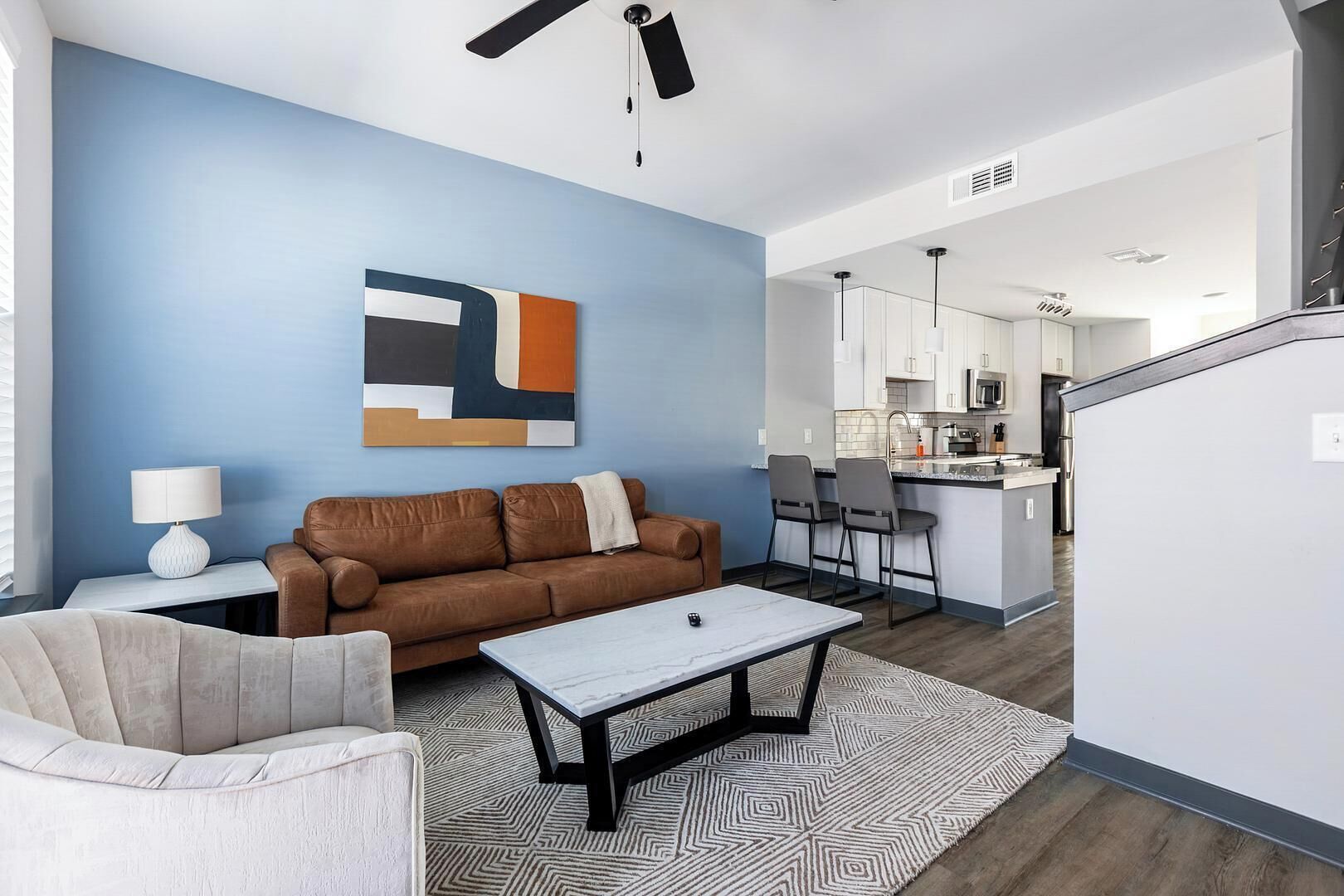 A modern living room with a brown sofa, a white coffee table, and a patterned rug.