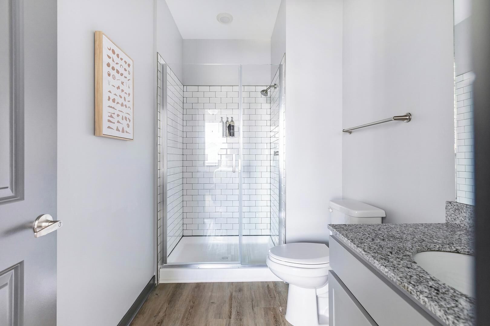 Un baño moderno con cabina de ducha de vidrio, inodoro y encimera de granito.