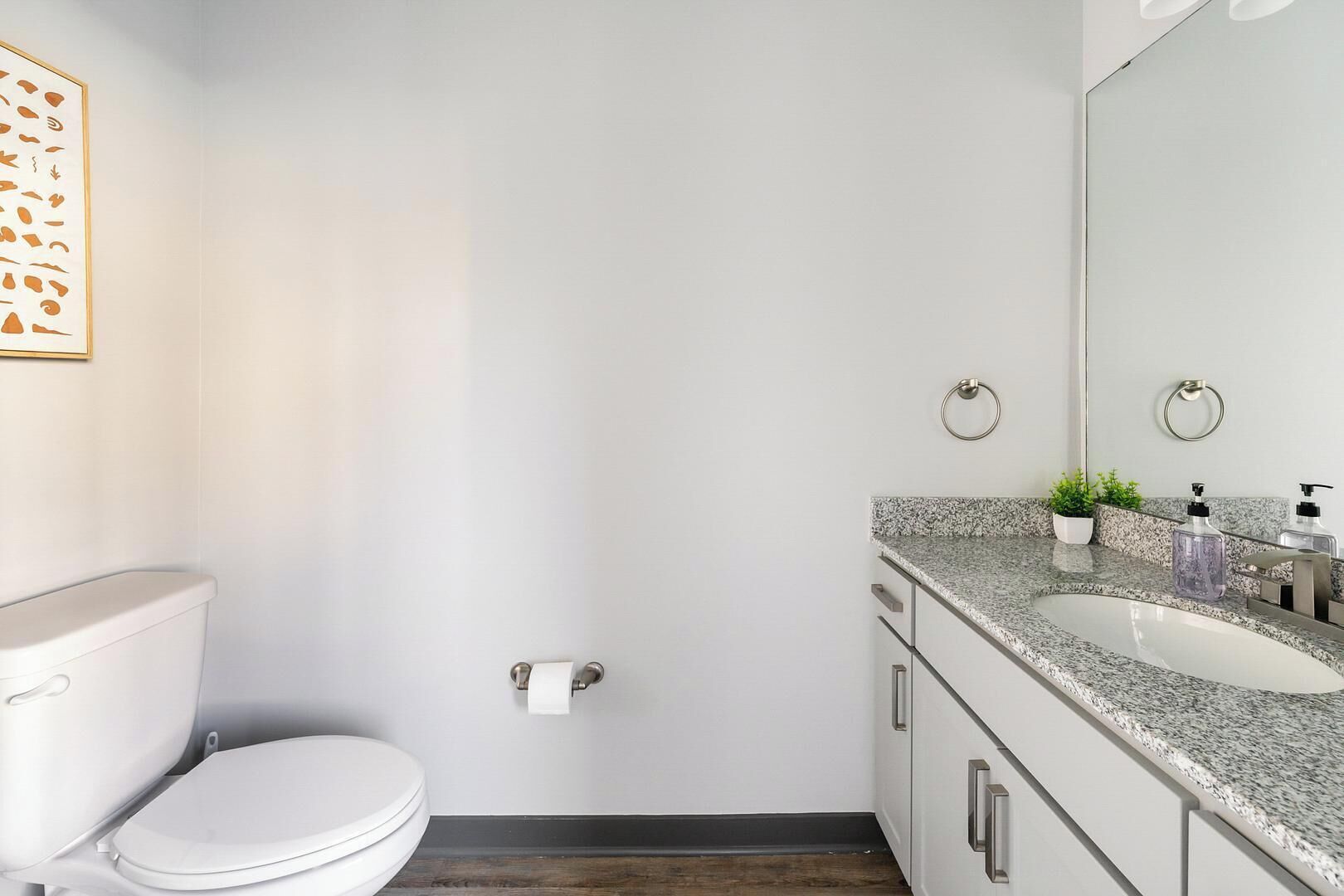 Een moderne badkamer met toilet, wastafel en spiegel.