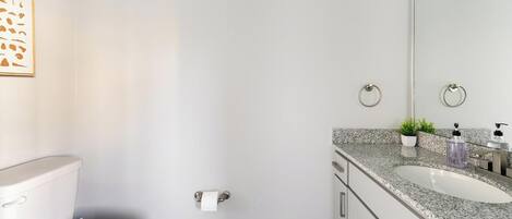 Een moderne badkamer met toilet, wastafel en spiegel.
