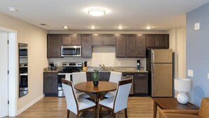 A modern kitchen with dark wooden cabinets, stainless steel appliances, and a granite countertop. - Landing | Stunning 2BD, Pool, Game Room (Spartanburg)