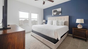A bedroom with a large bed, a nightstand, a dresser, and a ceiling fan. - Landing | Modern 2BD, Gym, Game Room (Buda)
