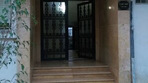 Ein Gebäudeeingang mit einer Treppe, die zu einem verschlossenen Portal führt.
