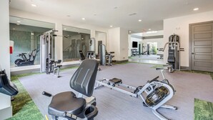 A gym with various exercise equipment, including a stationary bike, elliptical, and weight machines. - Landing | Beautiful 2BD, Gym, Pool (Charlotte)