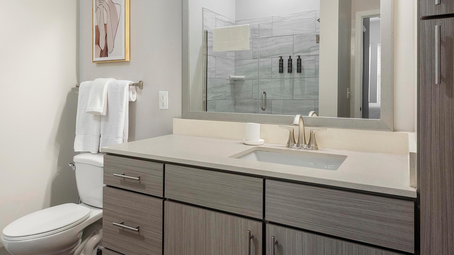 A modern bathroom with a toilet, a sink, and a mirror.
