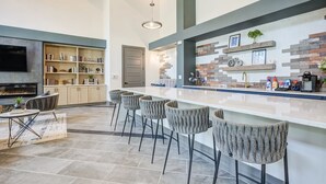 A modern kitchen with a long island, bar stools, and a built-in TV. - Landing | Beautiful 2BD, Gym, Pool (Charlotte)