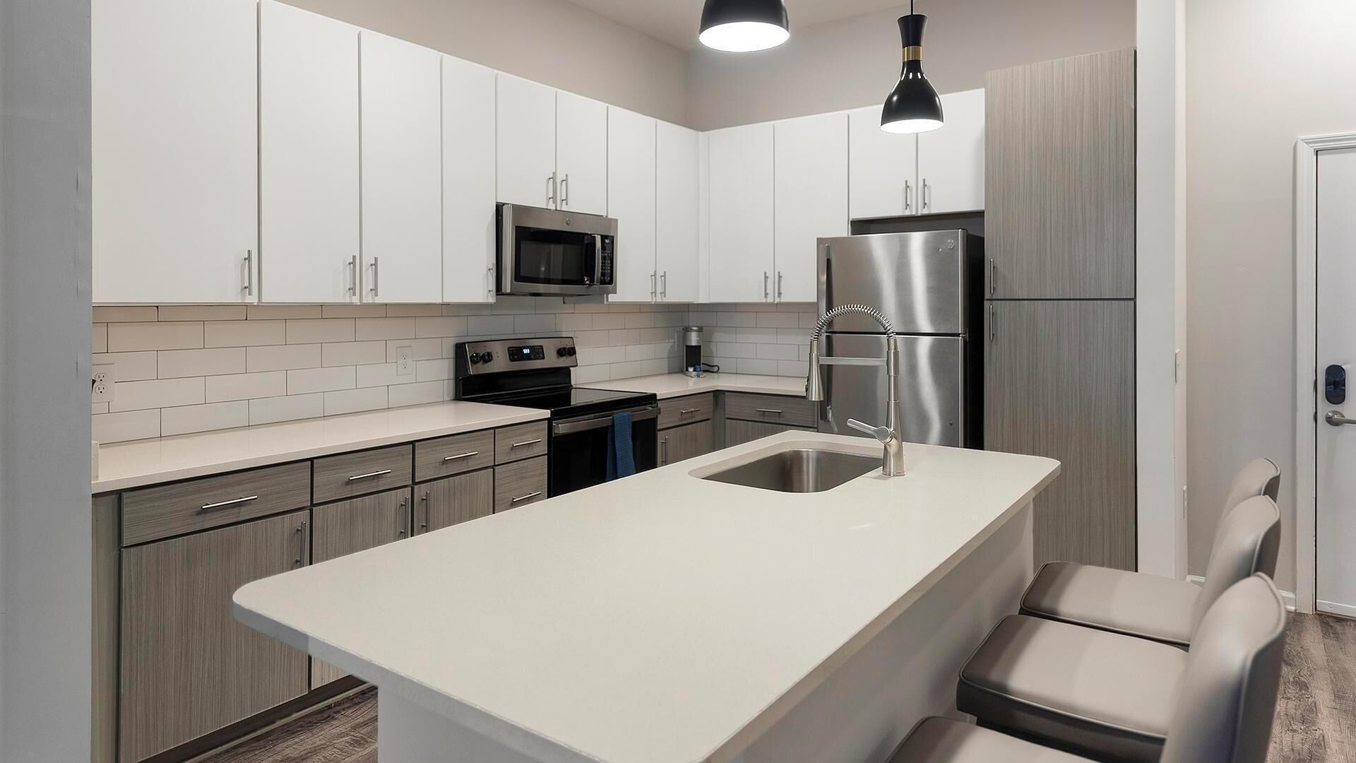 Een moderne keuken met witte kastjes, roestvrijstalen apparatuur en een centraal kookeiland met zitplaatsen.