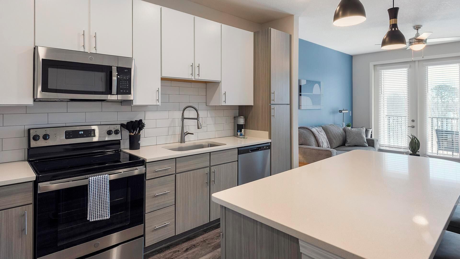 A modern kitchen with stainless steel appliances, a large island, and a view to a living area.