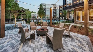 Eine Terrassenfläche mit Korbmöbeln, einem Feuerkorb und einem Pool im Hintergrund.