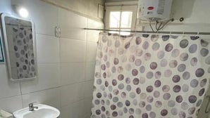Une salle de bain avec un lavabo sur colonne, des toilettes et un rideau de douche à motifs à pois.