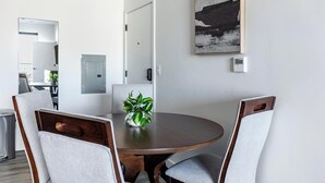 Un comedor con una mesa redonda, cuatro sillas, una planta en maceta y un cuadro en la pared.
