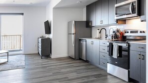 A modern kitchen with grey cabinets, stainless steel appliances, and a wooden floor. - Landing | Spectacular 1BD in Central City (Salt Lake City)