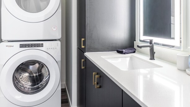 A modern laundry room with stacked washers and dryers, a sink, and a window. - Landing | Spectacular 1BD in Central City (Salt Lake City)