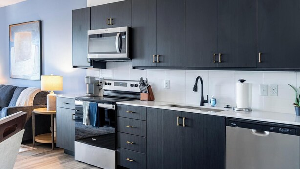 A modern kitchen with dark cabinetry, a built-in microwave, a stove, and a dishwasher. - Landing | Modern 1BD in Central City (Salt Lake City)