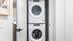 A compact, two-door laundry room with a modern design, featuring two stacked Whirlpool washing machines. - Landing | Modern 1BD in Central City (Salt Lake City)