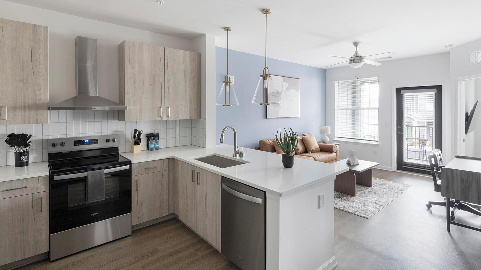 A modern kitchen with a central island, stainless steel appliances, and light wood cabinetry.