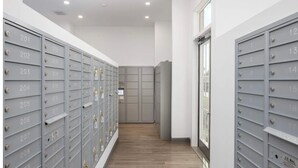 A row of grey mailboxes with numbers, a wooden floor, and a door at the end.