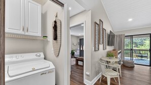 A laundry area with a washer and dryer, a dining area with a table and chairs, and a view of a balcony with outdoor furniture.