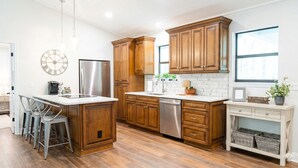 A modern kitchen with wooden cabinets, stainless steel appliances, and a marble backsplash.