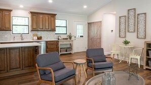 A spacious kitchen with wooden cabinets, a large island, and a dining area with two chairs and a small table.