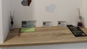 Eine Wand mit herzförmigen Ausschnitten und ein Holzregal mit einem Stift, einem Notizblock und zwei Visitenkarten.