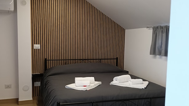 Ein modernes Schlafzimmer mit einem Bett, einer Wand aus Holzleisten und einer Deckenleuchte.