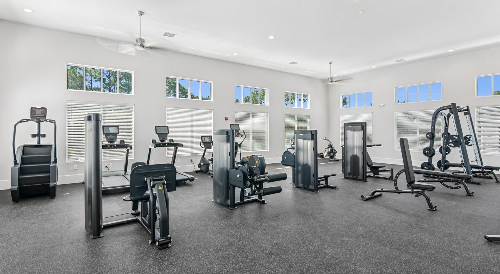 Une salle de sport équipée de tapis de course, d’appareils de musculation et de poids libres.