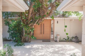 A wooden door with a glass panel, surrounded by greenery and a stone statue. - Casa Musica - Spectacular Villa With Harbour View (Saint Paul)