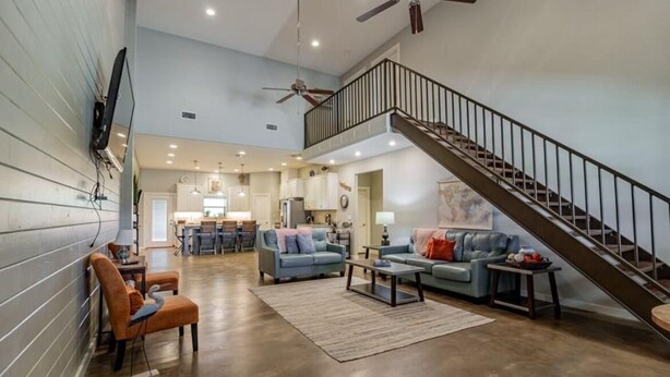 A spacious living room with a high ceiling, a staircase, and a kitchen in the background. - POC 4 Bedroom, 3 bath Barndominium close to Froggies and 5D (Port Lavaca)
