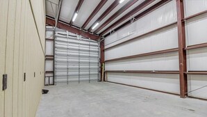 A large, empty industrial-style garage with metal doors and a concrete floor. - POC 4 Bedroom, 3 bath Barndominium close to Froggies and 5D (Port Lavaca)