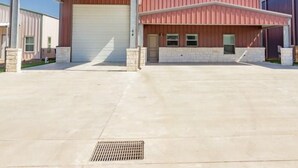 A large industrial building with a covered loading dock and a main garage door. - POC 4 Bedroom, 3 bath Barndominium close to Froggies and 5D (Port Lavaca)