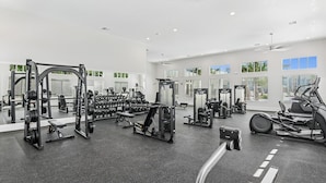 A modern gym with various exercise equipment, large windows, and a spacious layout. - Landing | Chic 2BD, Pool, Clubhouse (Palm Bay)