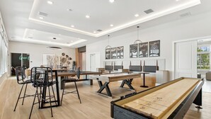 Um quarto amplo com mesa de bilhar, mesa de futebol e área de refeições com cadeiras e mesa.