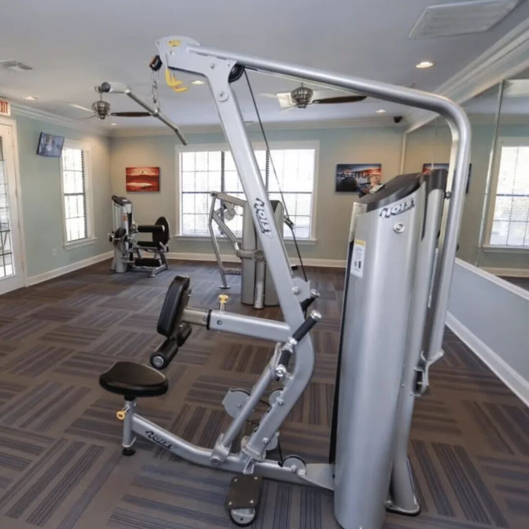 Une salle de sport équipée de divers appareils d’exercice, d’un banc et d’un téléviseur fixé au mur.
