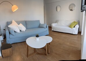 A living room with a blue sofa, a white sofa, a round white table, and a small plant. - Fabulous 2-bedroom apartment with AC in charming Granada (Granada)
